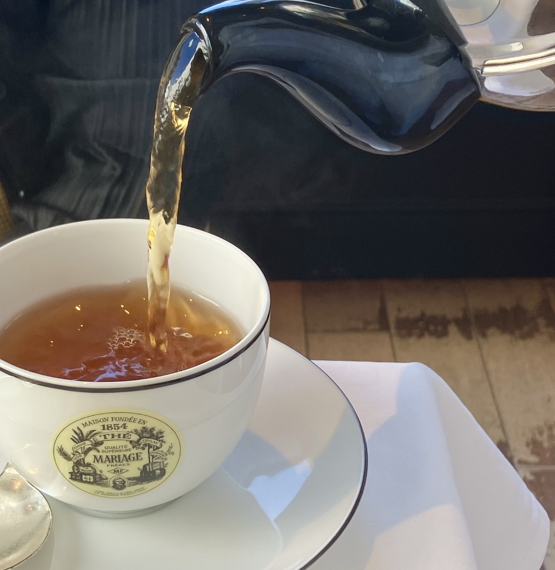 マリアージュフレール銀座松屋通り店で、ポットからティーカップへ紅茶が注がれる優雅な瞬間。高級感あふれるサロン・ド・テの風景。
