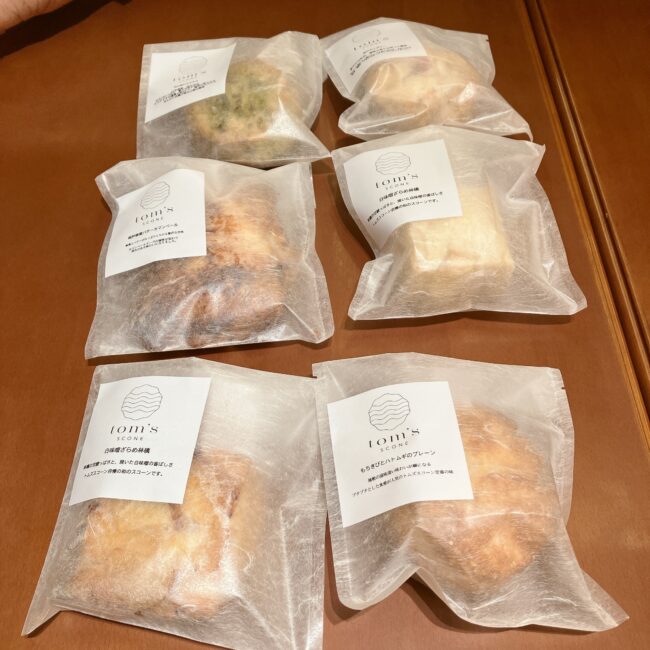 友人が購入した「tom's SCONE（トムズスコーン）」の6つのスコーン。「白味噌ざらめ林檎」や「もちきびとハトムギのプレーン」など、和の素材を使ったフレーバーが個包装されている。