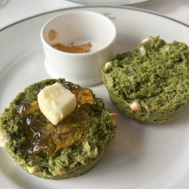 宇治抹茶スコーンの断面。ホワイトチョコが練り込まれた生地に、ダージリンインペリアルの紅茶ジャムとバターが乗っている。