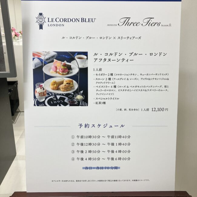 ル・コルドン・ブルー・ロンドンとスリーティアーズのコラボアフタヌーンティーの案内看板。メニュー詳細と12,100円という価格、1日4回の予約スケジュールが記載されている。