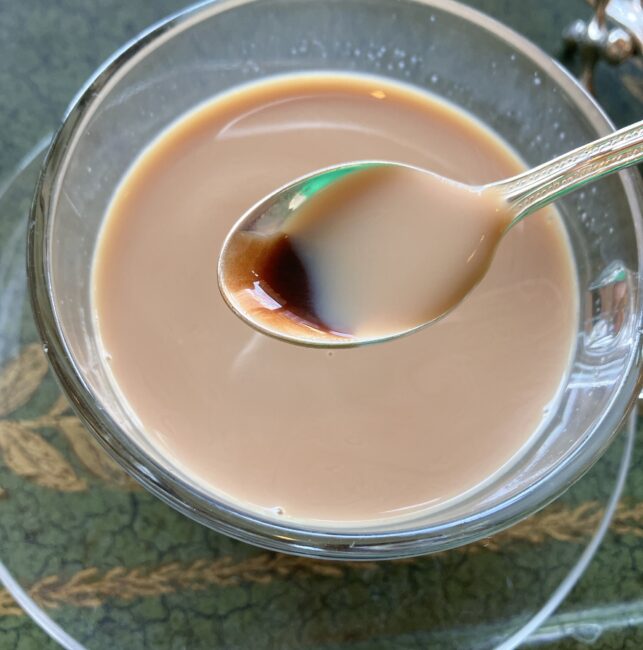 ガラスカップに入ったストロベリーミルクティーの上に、小さな銀のスプーンに乗せられた、濃厚なチョコレートソースが溶け出そうとしている瞬間。