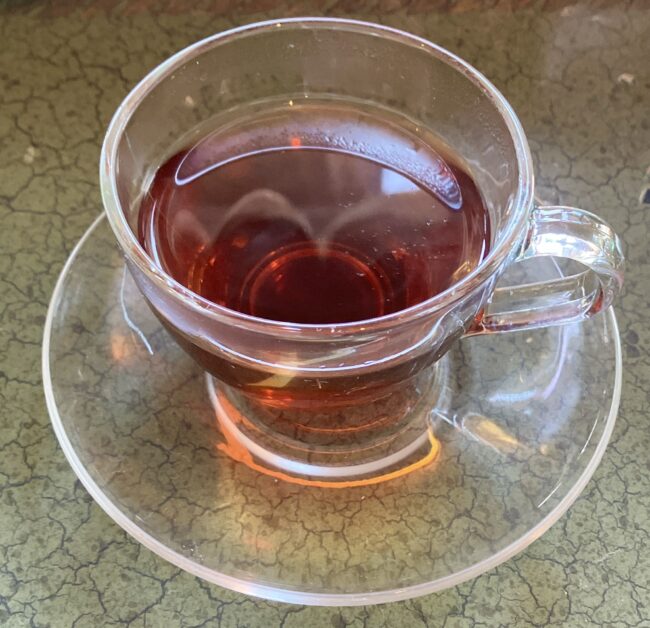 ガラスカップに注がれた、琥珀色の「桜」のフレーバードティー。光を受けて美しく輝いている。