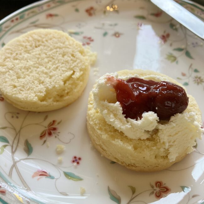 ナイフで横半分に切られたプレーンスコーンの美しい断面。その上にたっぷりのクロテッドクリームとジャムが乗っている。
