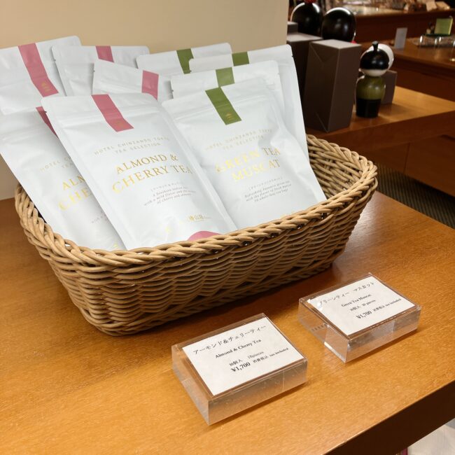 ホテル椿山荘東京のショップ「セレクションズ」で販売されているオリジナルティーのパッケージ。「アーモンド＆チェリーティー」と「グリーンティー マスカット」のティーバッグ商品がカゴに陳列されている。