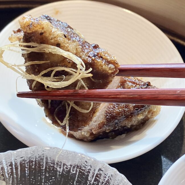 ジャヌ東京「虎景軒」のアフタヌーンティーのサボリ。「黒毛和牛フィレ肉 黒胡椒炒め」を箸で持ち上げたクローズアップ写真。肉の表面が香ばしく焼け、シズル感が伝わる。