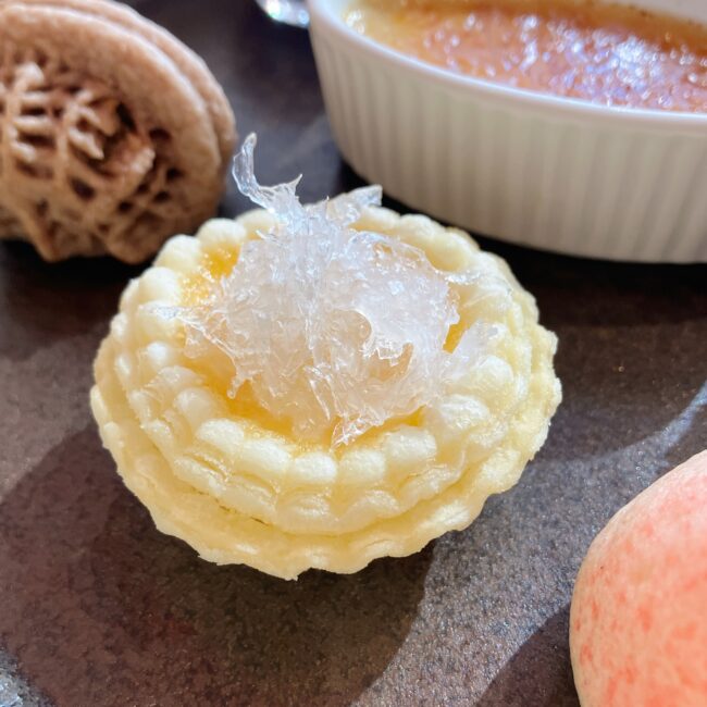 ジャヌ東京「虎景軒」のアフタヌーンティーのスイーツ。「燕の巣のせエッグタルト」のクローズアップ写真。タルトの上にたっぷりと燕の巣が鎮座しているのがわかる。シズル感が伝わる。