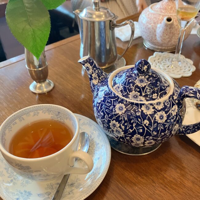 タイニートリアの1杯目の紅茶（リーフティー）。ブルーの小花柄が可愛らしいバーレイのティーポットとティーカップ。奥には、紅茶の濃さを自分好みに調整するための「差し湯」が入ったシルバーポットが用意されている。