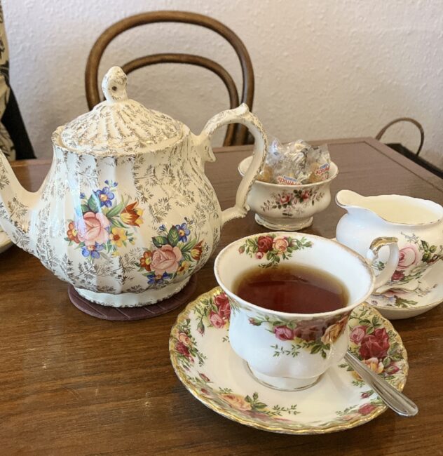 タイニートリアの紅茶サービス。華やかな花柄と金彩が施されたクラシカルなティーポットとティーカップ。奥にはシュガーボウルとミルクジャグもセットされており、優雅なティータイムの雰囲気が伝わる。