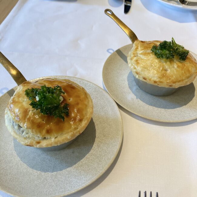 帝国ホテル京都アフタヌーンティーの温かいお料理「牛ほほ肉のパイ包み」。金色の持ち手がついた可愛らしい小鍋に入った、こんがり焼き上がったパイが2つ並んでいる。