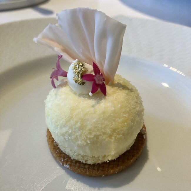 帝国ホテル京都アフタヌーンティーの「カマンベールチーズケーキ」。舞妓さんの華やかな装飾をイメージし、可憐な花や金箔、白いチョコレートの飾りが施されている。