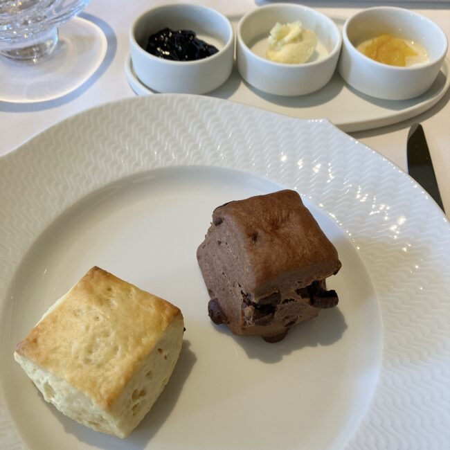 帝国ホテル京都アフタヌーンティーのプレーンスコーンとチョコレートスコーン。奥にはブルーベリージャム、クロテッドクリーム、ゆずジャムが添えられている。