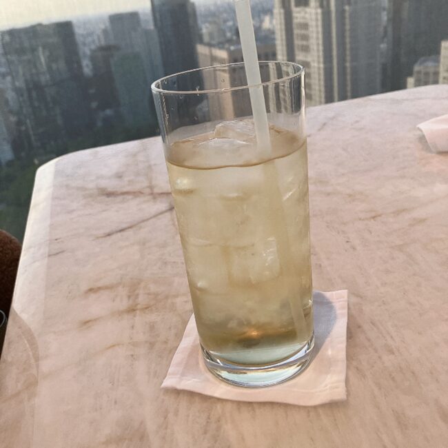 夕暮れの東京のビル群を背景にした、冷たいアイスハーブティー(スージング)。