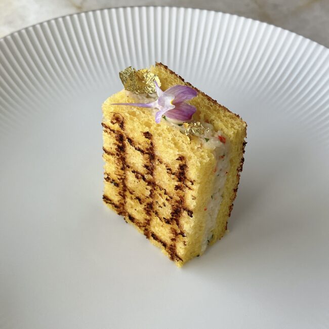 パークハイアット東京のアフタヌーンティー。ズワイ蟹と新じゃが芋のサンドウィッチ。金箔と紫の花が飾られた高級感のある仕上がり。