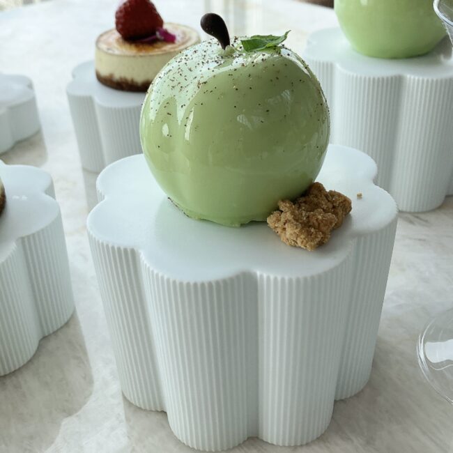 パークハイアット東京の「BIG APPLE」スイーツ。鮮やかなグリーンのリンゴの形をしたケーキが、白い陶器のスタンドに載っている。