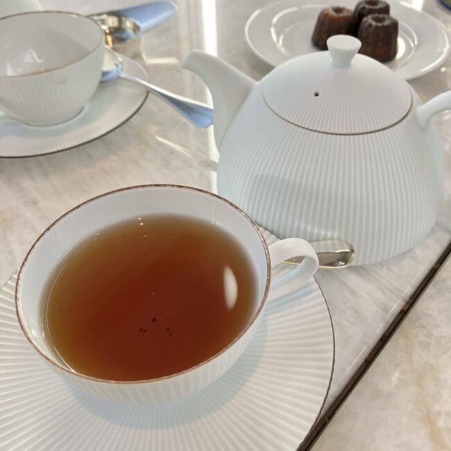 デカフェ(カフェインレス)のアールグレイティー。奥には食べ放題メニューのカヌレが並んでいる。