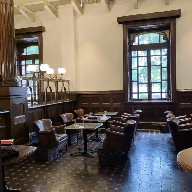 かつての銀行窓口の面影を残す「Café 1894」のクラシカルな店内と、ゆったりくつろげる革張りソファの座席。