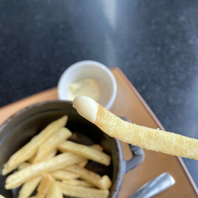 熱々のトリュフポテトに白いディップソースをたっぷりつけている様子