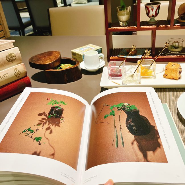 芝パークホテルのアフタヌーンティーのテーブル。開かれた美しい植物の写真集の奥に、ティーフーズや紅茶が並んでいる。