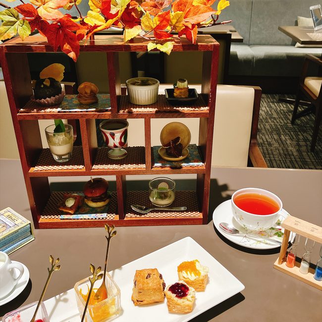 本棚をモチーフにした木製のティースタンド。秋の紅葉があしらわれ、和洋中の美しいティーフーズが並んでいる。