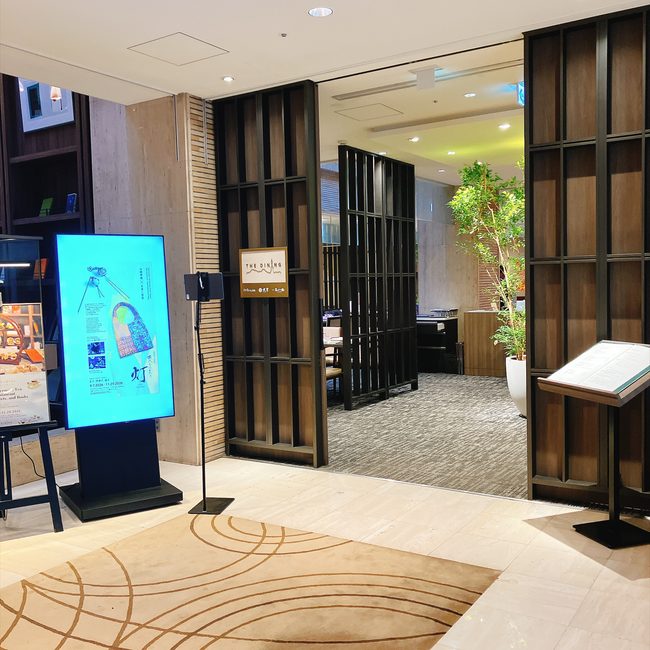 芝パークホテルのレストラン「ザ ダイニング」の入り口。モダンな格子のパーティションの奥に、緑あふれる店内が見える。